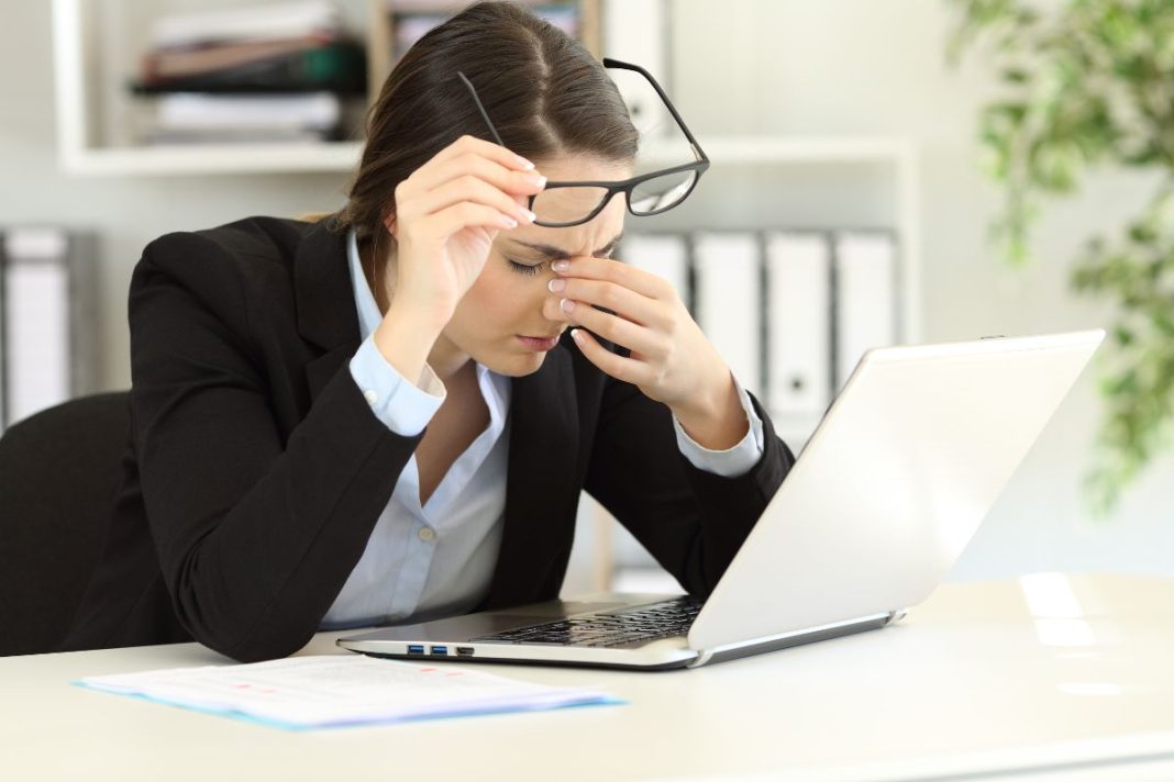 office-worker-suffering-eyestrain-at-work office-worker-suffering-eyestrain-at-work