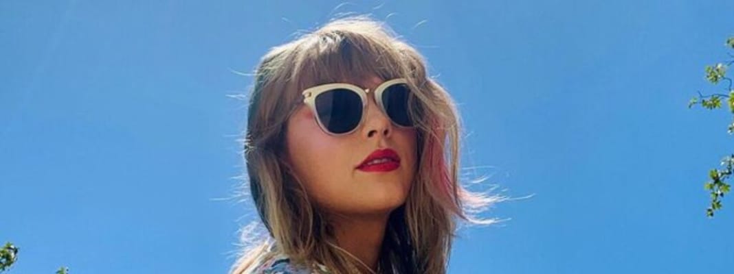 taylor-swift-glasses Taylor Swift wearing sunglasses and a floral top.