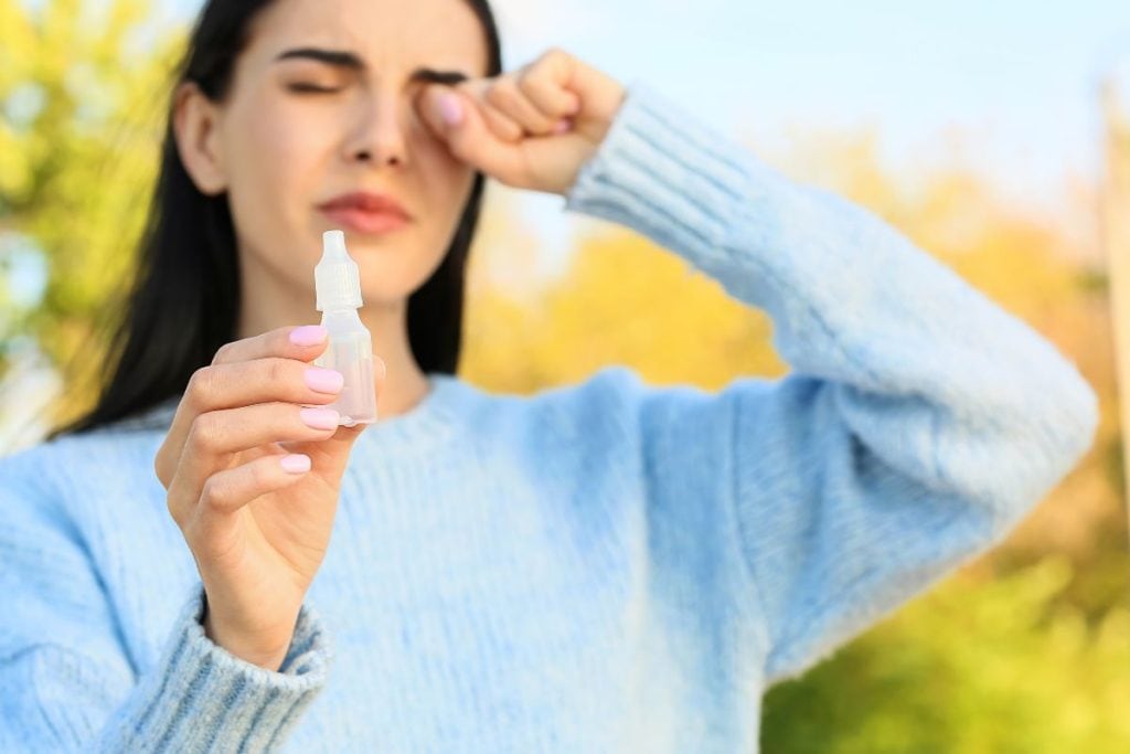 young-woman-holding-eye-drops-outdoors