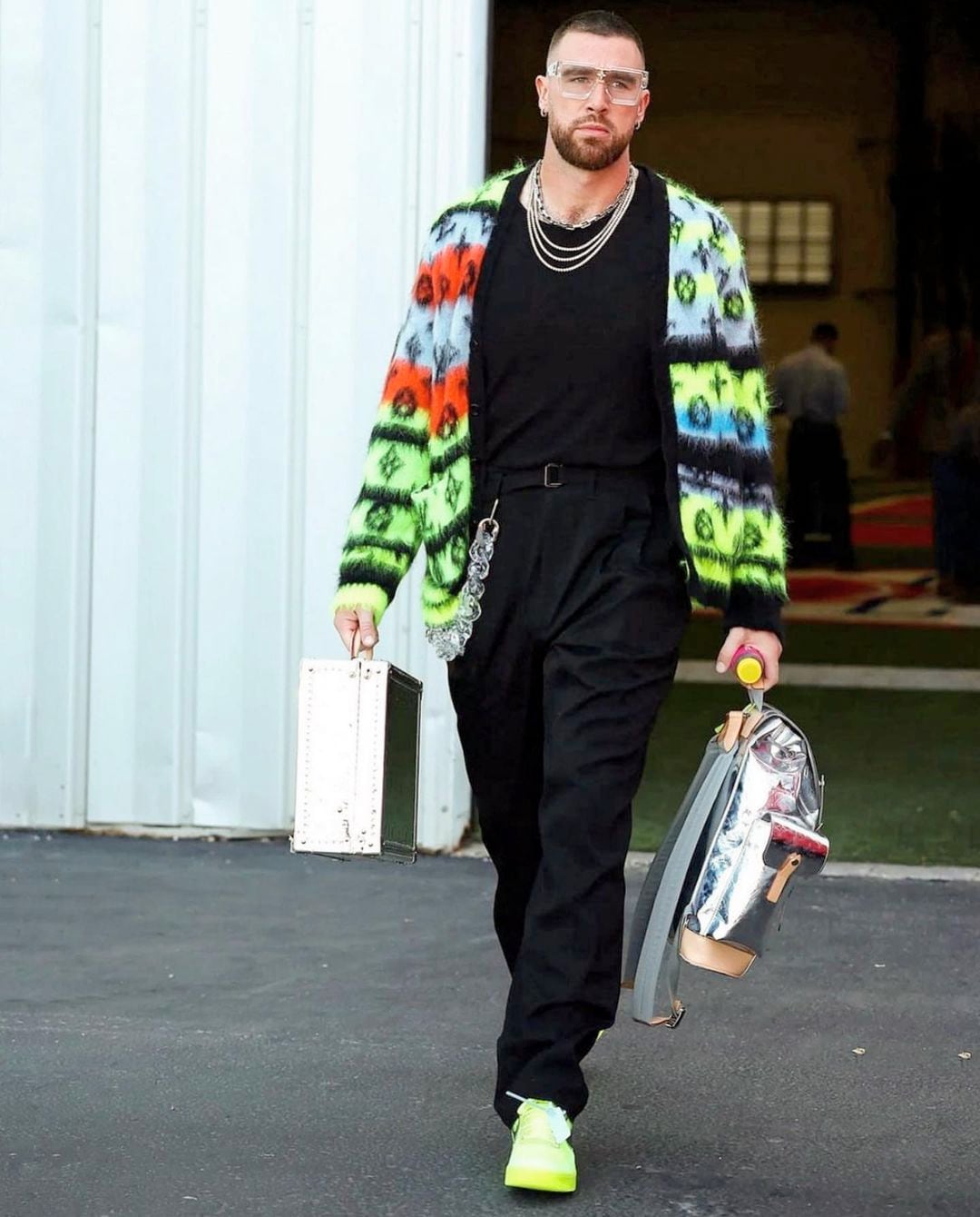 Travis Kelce wearing clear glasses and a bright outfit.