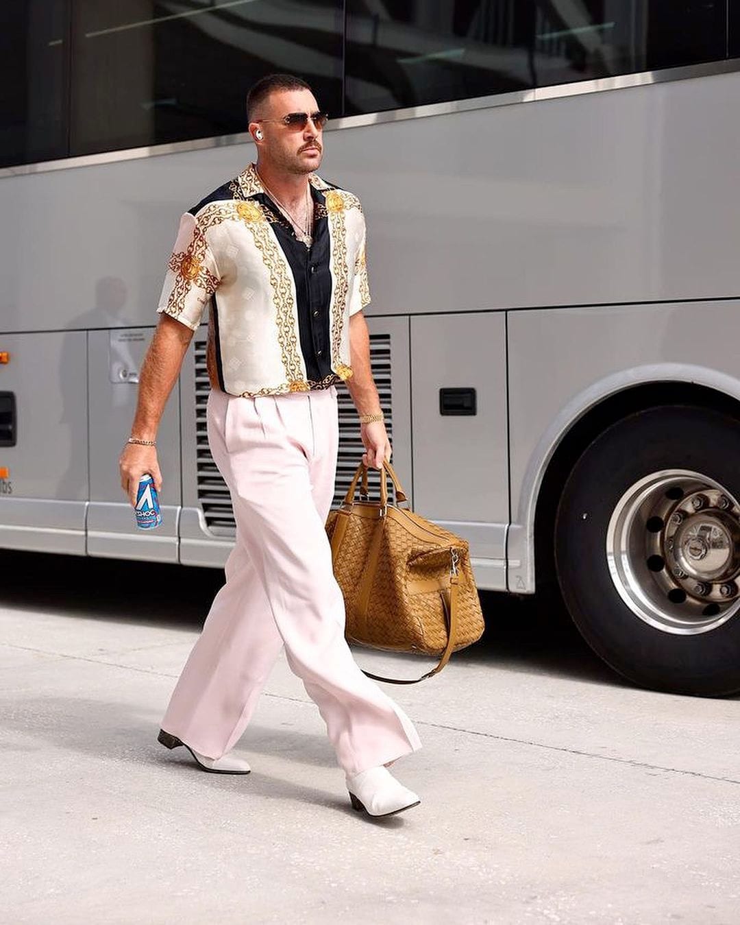 Travis Kelce wearing sunglasses and a neutral yet shimmering outfit.