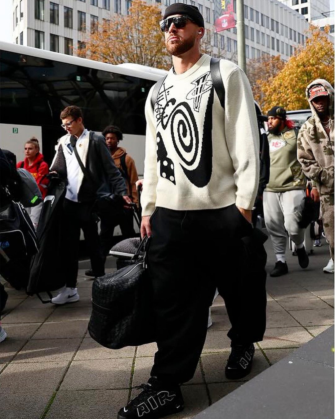 Travis Kelce wearing sunglasses and a two-toned outfit.