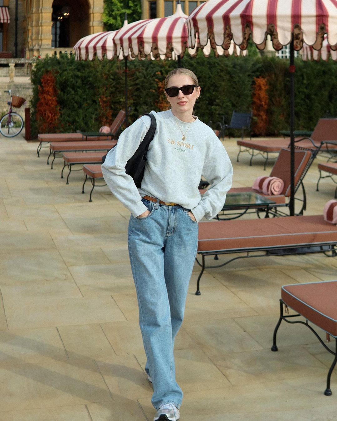 A woman wearing sweatshirt, denim jeans, and old-money-inspired sunglasses. 