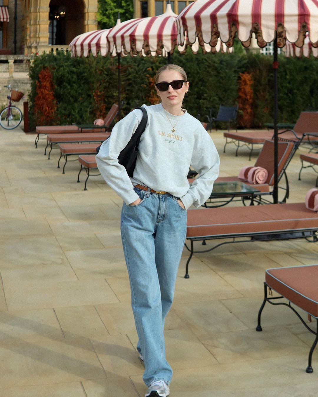 A woman wearing sweatshirt, denim jeans, and old-money-inspired sunglasses.