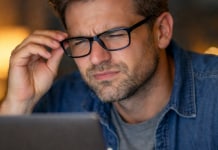 5 Signs It’s Time to Update Your Glasses Prescription (Don’t Wait!) Person wearing glasses squinting at a laptop screen.