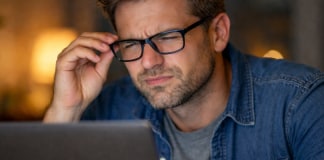 5 Signs It’s Time to Update Your Glasses Prescription (Don’t Wait!) Person wearing glasses squinting at a laptop screen.
